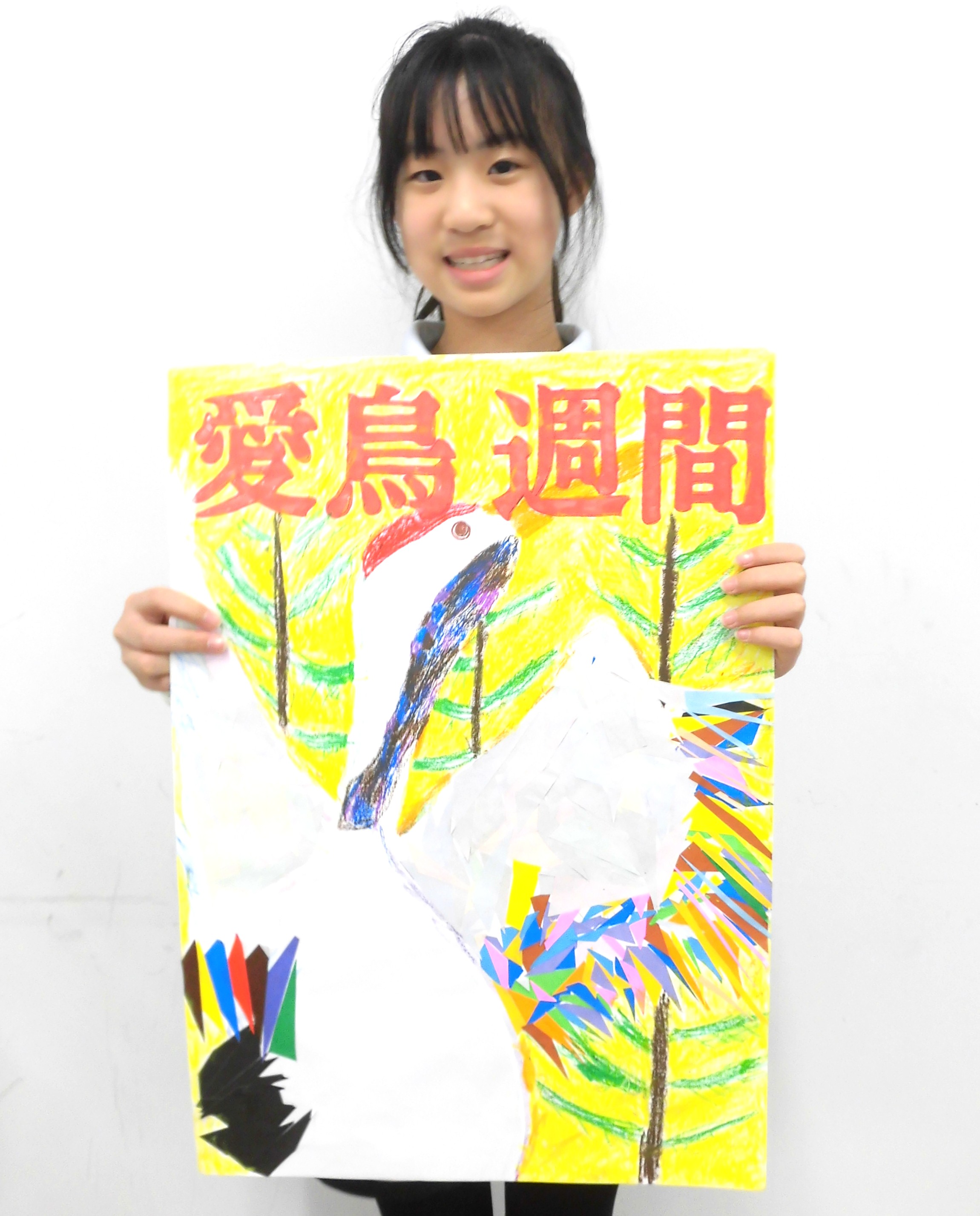 「優秀賞」倪 怡然さんより　工夫したところは、鶴の羽を、白と他の色の折り紙で細長い形や小さい形に切った所です。そして、鶴ののどのあたりを紫や青・茶色を組み合わせて塗り、夕日を目立たせるために鶴のラインをオレンジにしました。
